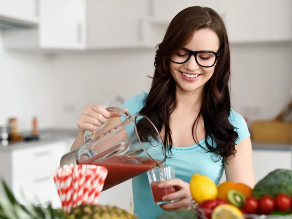 Happy woman pouring the fresh juice in the glass 