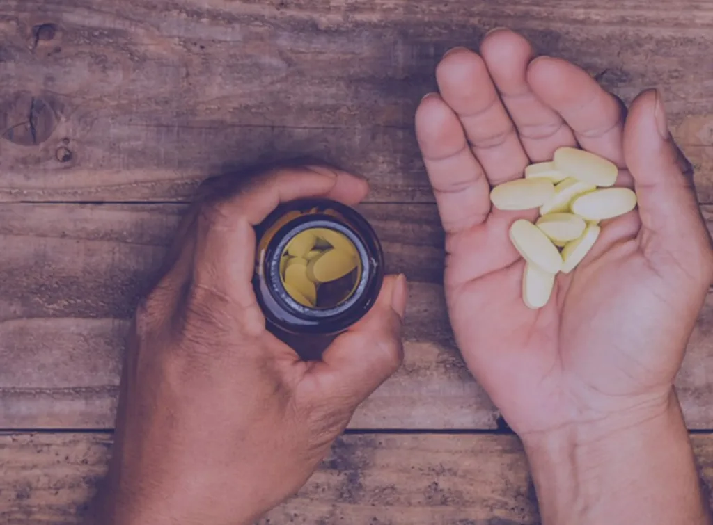 Hands holding health supplement tablets and the bottle